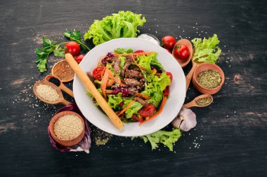 Dana eti ve mantar sebze salatası. Siyah ahşap arka plan üzerinde. Üstten Görünüm. Metniniz için kopya alanı.