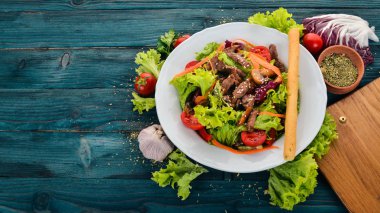 Dana eti ve mantar sebze salatası. Mavi ahşap arka plan üzerinde. Üstten Görünüm. Metniniz için kopya alanı.