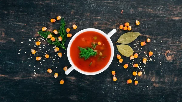 Tomato soup with chili and vegetables. Healthy food. On a black wooden background. Top view. Copy space for your text.