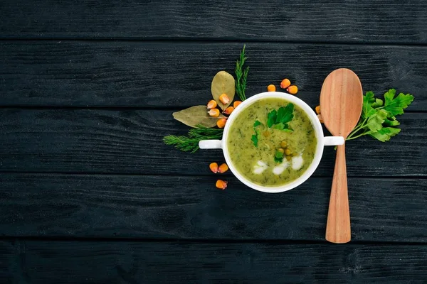 Soup with broccoli and peas and vegetables in a bowl. Healthy food. On a black wooden background. Top view. Copy space for your text.