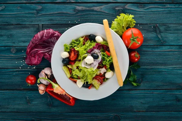 Mozzarella ve taze sebze salatası. Mavi ahşap arka plan üzerinde. Üstten Görünüm. Metniniz için kopya alanı.