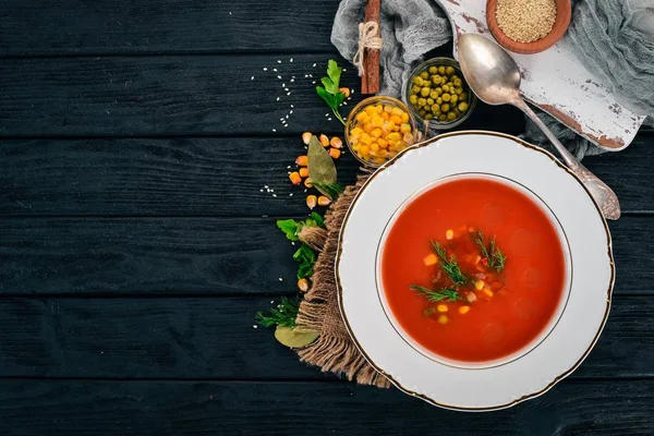 Tomato soup with chili and vegetables. Healthy food. On a black wooden background. Top view. Copy space for your text.