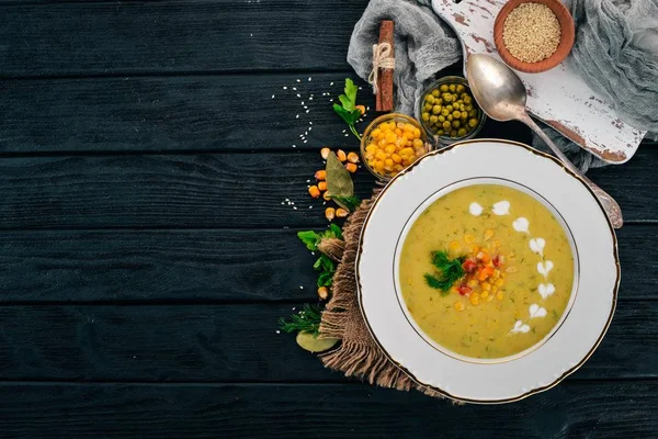 Corn soup with fresh vegetables in a bowl. Healthy food. On a black wooden background. Top view. Copy space for your text.