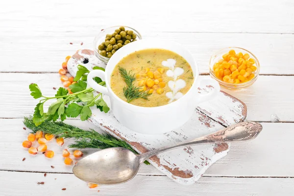 Corn soup with fresh vegetables in a bowl. Healthy food. On a white wooden background. Top view. Copy space for your text.