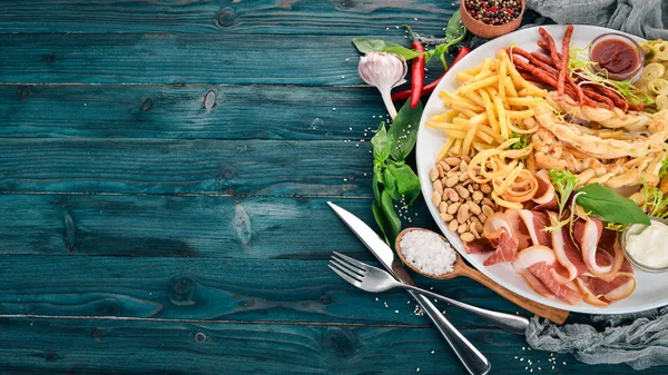 A selection of snacks for beer. Chips, sausage, cheese. Top view. On a wooden background. Copy space.