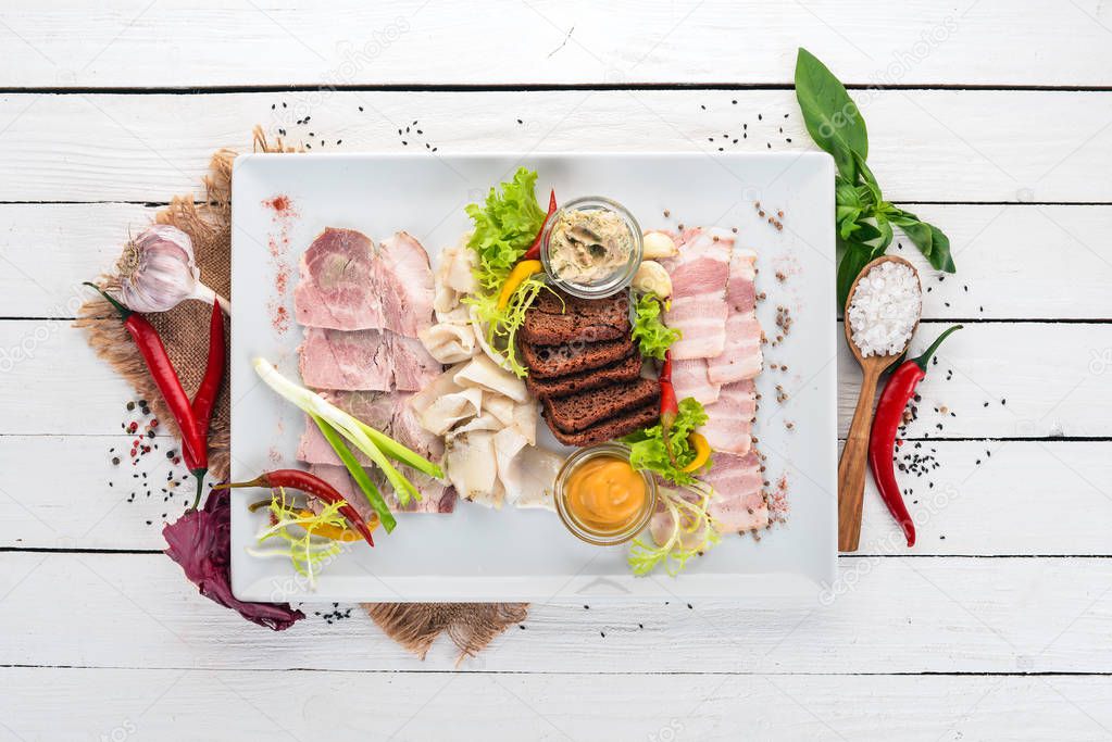 Meat sliced on a plate. Mustard, horseradish. Top view. On a wooden background. Copy space.