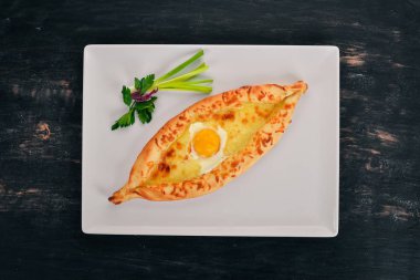 Khachapuri yumurta ve peynir ile. Gürcü mutfağı. Üstten Görünüm. Ahşap bir arka plan üzerinde. Kopya alanı.