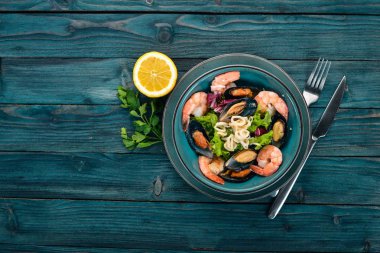 Bir tabak deniz ürünleri. Midye, mürekkep balığı, karides. Üstten Görünüm. Mavi ahşap arka plan üzerinde. Kopya alanı.