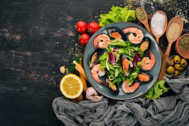 Bir tabak deniz ürünleri. Midye, mürekkep balığı, karides. Üstten Görünüm. Siyah ahşap arka plan üzerinde. Kopya alanı.