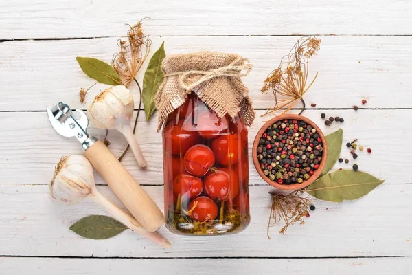 Marinated cherry tomatoes in a jar. Stocks of food. Top view. On a wooden background. Copy space.