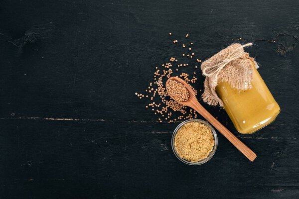 Mustard Sauce. Spices On a black wooden background. Top view. Copy space for your text.