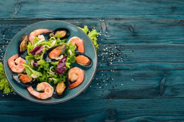 Bir tabak deniz ürünleri. Midye, mürekkep balığı, karides. Üstten Görünüm. Mavi ahşap arka plan üzerinde. Kopya alanı.