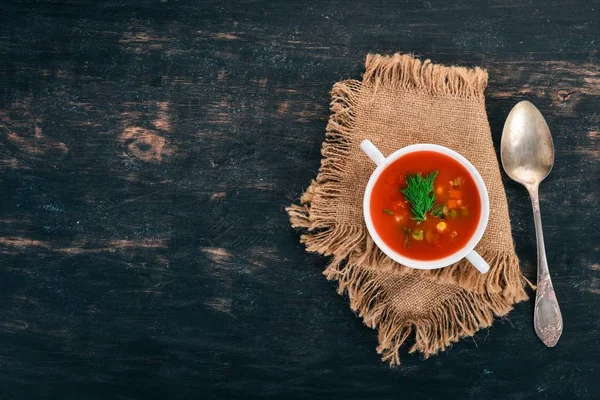 Tomato soup with chili and vegetables. Healthy food. On a black wooden background. Top view. Copy space for your text.