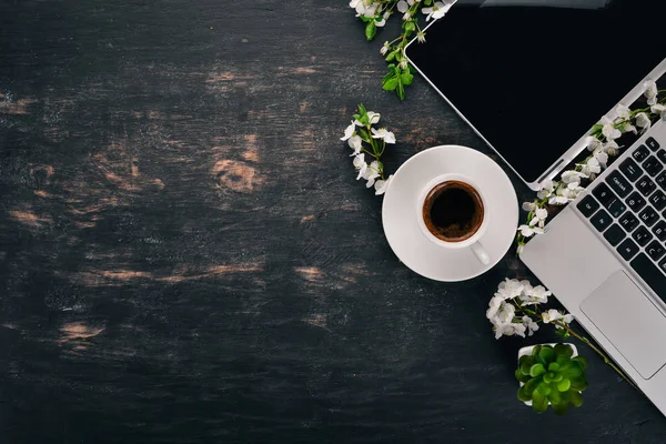 Laptop with coffee and flowers. Business. On a wooden background. Top view. Copy space.