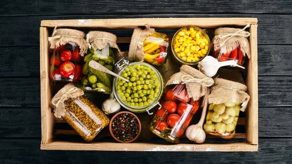 Pickled foods in cans. Stocks of food. Top view. On a wooden background. Copy space.