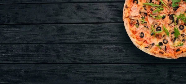 Pizza capricciosa. Mozzarella, ham, mushrooms, olives. Top view. On a wooden background. Copy space.