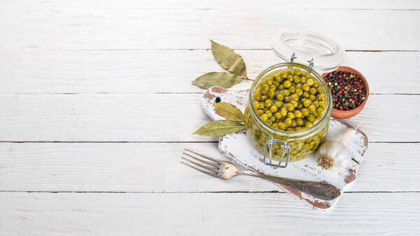 Маринованный зеленый горошек в банке. Запасы еды. Вид сверху. На деревянном фоне. Копирование пространства
.
