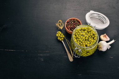 Bir kavanoz turşu yeşil bezelye. Gıda stokları. Üstten Görünüm. Ahşap bir arka plan üzerinde. Kopya alanı.