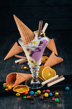 Vanilyalı dondurma ile renkli şekerler. Siyah ahşap arka plan üzerinde. Kopya alanı.
