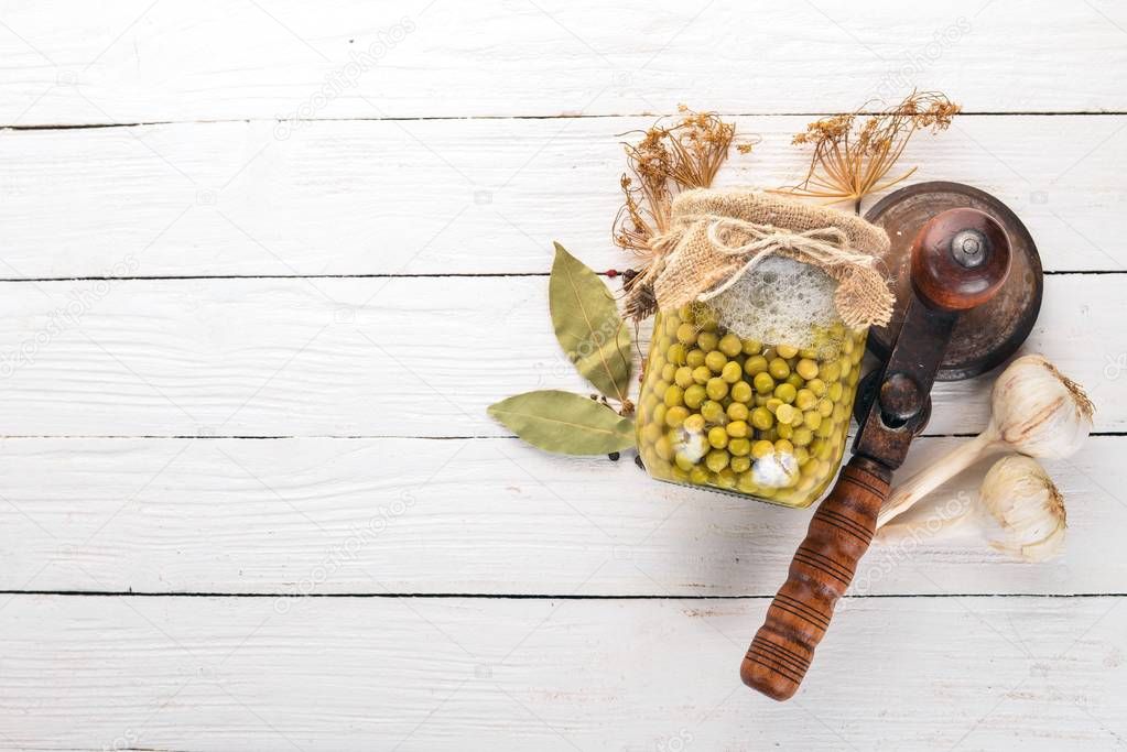 Pickled green peas in a jar. Stocks of food. Top view. On a wooden background. Copy space.