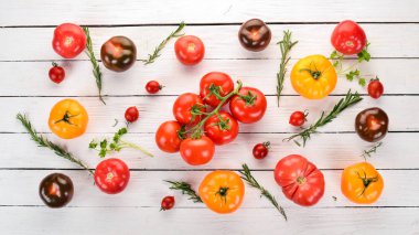 Beyaz ahşap arka plan üzerinde renkli domates. Üstten Görünüm. Kopya alanı.