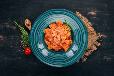 Farfalle makarna domates ve parmesan peyniri. Ahşap bir arka plan üzerinde. İtalyan mutfağı. Üstten Görünüm. Kopya alanı.