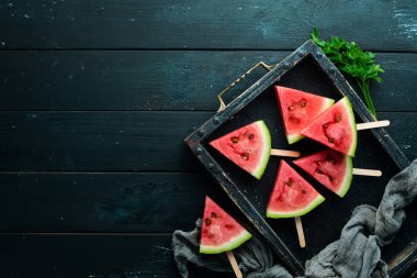 Siyah arka planda karpuz dondurması. Çubuklarda karpuz dilimleri. Üst Manzara. Boş kopyalama alanı.
