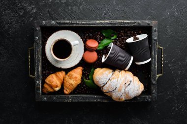 Bir fincan kruvasanla kahve. Kahvaltıda. Siyah taştan bir arka planda. Üst Manzara. Metnin için boş yer.