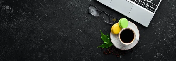 A cup of coffee with a macaroons cake. On a black stone background. Top view. Free space for your text.