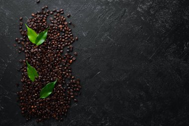 Roasted coffee beans. On a black stone background. Top view. Free space for your text. clipart