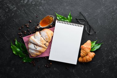 Kahvaltıda. Taze çikolatalı kruvasan. Siyah taştan bir arka planda. Üst Manzara. Metnin için boş yer.