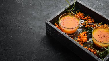 Deniz dikenli üzümlerden iç. Sıcak kış içeceği. Dal üzerinde taze deniz dikenleri. Üst Manzara. Metnin için boş yer.