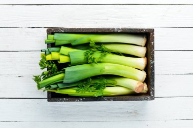 Siyah taştan bir arka planda tahta bir kutuda taze pırasa. Üst Manzara. Boş kopyalama alanı.