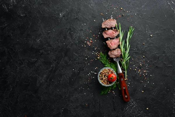 在叉子上烤小牛肉 黑石质背景的牛肉牛排 顶部视图 给你的文章腾出地方 — 图库照片