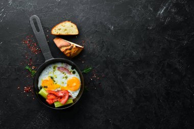 Kahvaltıda. Kızartma tavasında domuz pastırması ve sebzeli yumurta. Üst Manzara. Boş kopyalama alanı.