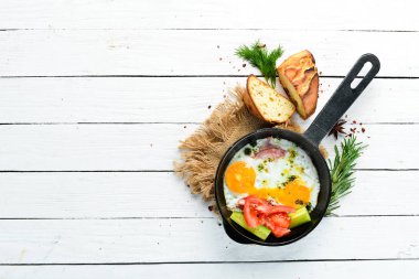 Kahvaltıda. Kızartma tavasında domuz pastırması ve sebzeli yumurta. Üst Manzara. Boş kopyalama alanı.