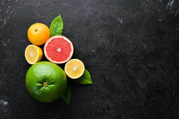 Fresh citrus fruits on black stone background. Top view. Free copy space.