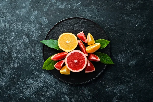 Fresh citrus fruits on black stone background. Top view. Free copy space.