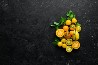 Siyah taş zemin üzerinde sarı domatesler. Üst Manzara. Metnin için boş yer.