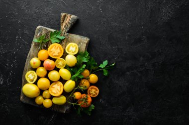 Siyah taş zemin üzerinde sarı domatesler. Üst Manzara. Metnin için boş yer.