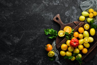 Siyah taş zemin üzerinde sarı domatesler. Üst Manzara. Metnin için boş yer.