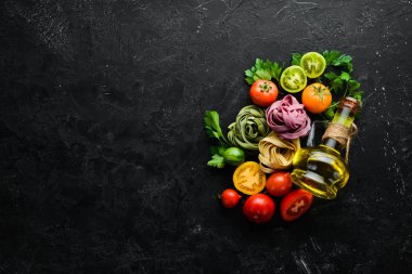 Makarna arka planı. Kuru makarna tagliatelle ve siyah arka planda malzemeler. Üst Manzara. Metnin için boş yer.