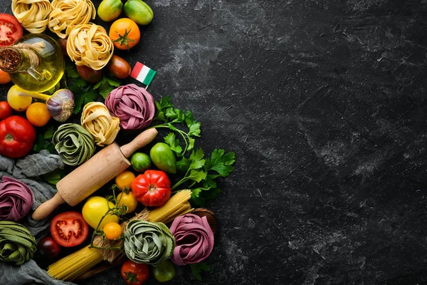Pasta background. dry pasta tagliatelle and ingredients on black background. Top view. Free space for your text.