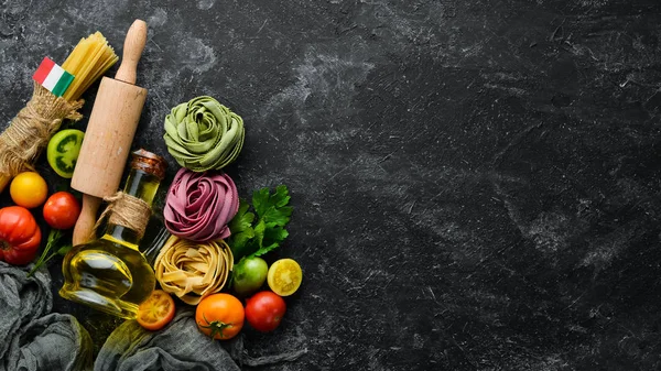 Pasta background. dry pasta tagliatelle and ingredients on black background. Top view. Free space for your text.