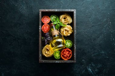 Kuru makarna, domates, yeşillik, yağ ve malzemeler. İtalyan geleneksel mutfağı. Taze sebzeler. Üst Manzara. Metnin için boş yer.