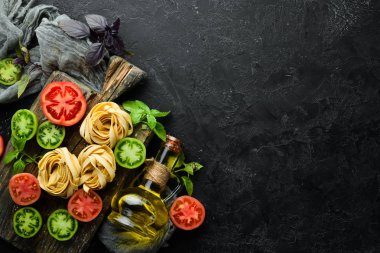 Kuru makarna, domates, yeşillik, yağ ve malzemeler. İtalyan geleneksel mutfağı. Taze sebzeler. Üst Manzara. Metnin için boş yer.