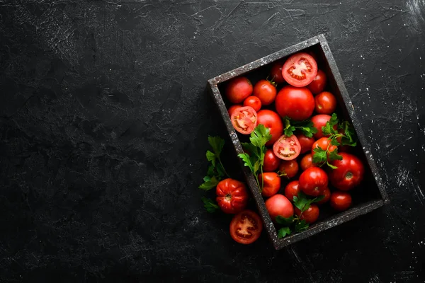 Fresh red tomatoes in box on black stone background. Vegetables. Top view. Free space for your text.
