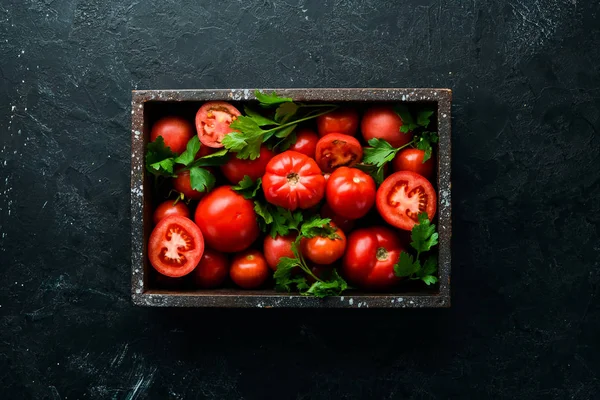 Fresh red tomatoes in box on black stone background. Vegetables. Top view. Free space for your text.