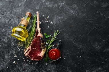 Kemiğe çiğ biftek. Siyah taştan bir arka planda Tomahawk bifteği. Üst Manzara. Metnin için boş yer.