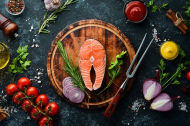 Siyah taşlı arka planda somon bifteği ve malzemeler. Üst Manzara. Metnin için boş yer.